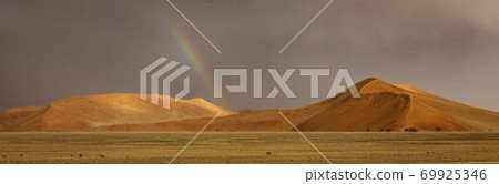Rainbow shines over a sand dune in the desert 69925346