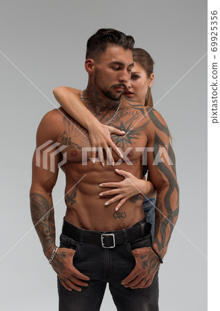 Woman hugging muscular man from behind Woman hugging muscular man from behind 69925356