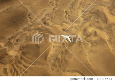 A microlight aircraft can be seen flying over the sands of Namibia 69925645