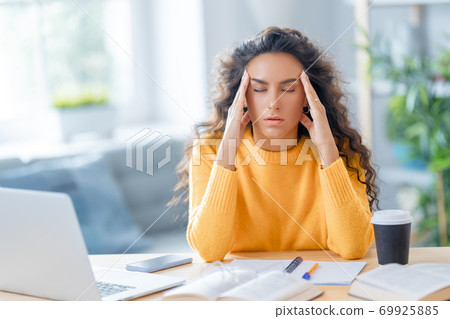 Young woman studying and having a head ache 69925885