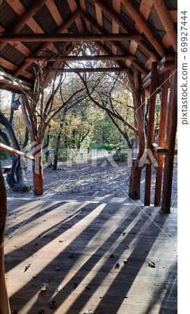Elvish wooden gazebo in the autumn forest with stylized trees with sunset rays 69927444