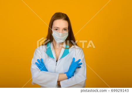 The caucasian girl in blue colored protective face mask on yellow background. The caucasian girl in blue colored protective face mask on yellow background. 69929143