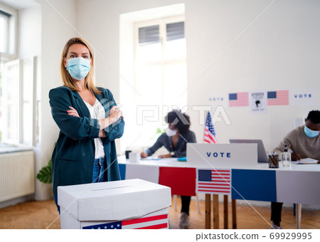 Young woman putting her vote in the ballot box, usa elections and coronavirus. 69929995