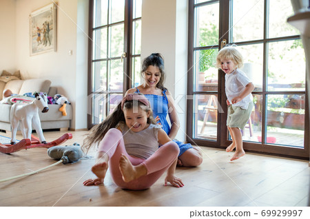 Pregnant woman with small children indoors at home, playing. 69929997