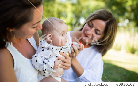 Woman with daughter and baby granddaughter resting outdoors in backyard. Woman with daughter and baby granddaughter resting outdoors in backyard. 69930108