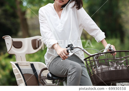 Woman calling while riding a bicycle Woman calling while riding a bicycle 69930338