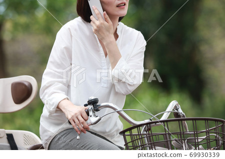 Woman calling while riding a bicycle 69930339