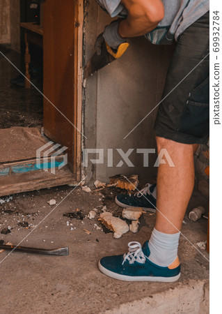 Dismantling of old entrance doors, old wooden box and door, the master cuts, cuts a wooden box from the wall with a hand saw. Dismantling of old entrance doors, old wooden box and door, the master cuts, cuts a wooden box from the wall with a hand saw. 69932784