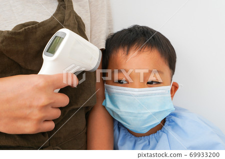 A nursery teacher who measures the temperature of an infant 69933200