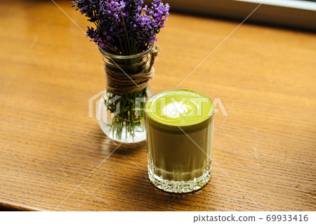 Green matcha beverage in glass on the wooden table Green matcha beverage in glass on the wooden table 69933416