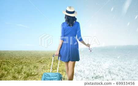 Asian woman with suitcase standing on the meadow field with winter and summer climate Asian woman with suitcase standing on the meadow field with winter and summer climate 69933456