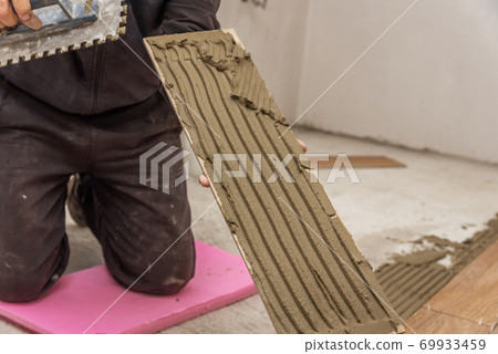 Worker placing ceramic floor. Worker placing ceramic floor. 69933459