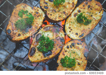 Cut and Grilled potato with charcoal fire. 69933489