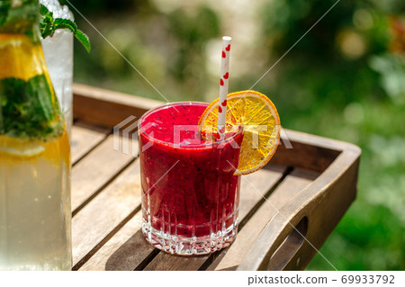 Red berry smoothie in a glass with a straw Red berry smoothie in a glass with a straw 69933792