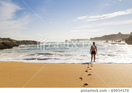 woman walking on the sand of a beautiful beach 69934178