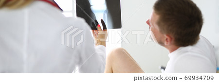 Doctor and patient are looking at an xray of leg. 69934709