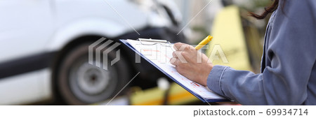 Insurance agent fills out paperwork after accident. Insurance agent fills out paperwork after accident. 69934714