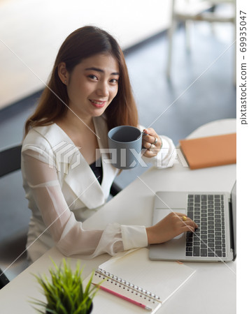Businesswoman working while drinking a cup of coffee 69935047