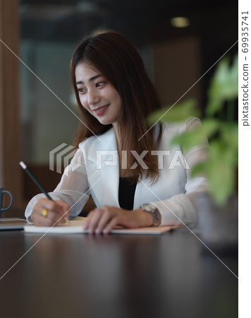 Female office worker working with stationery on table in office room 69935741
