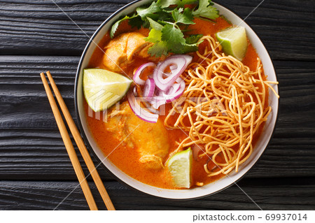 Coconut curry soup with chicken, fried noodles and spices. Thai style. horizontal top view Coconut curry soup with chicken, fried noodles and spices. Thai style. horizontal top view 69937014