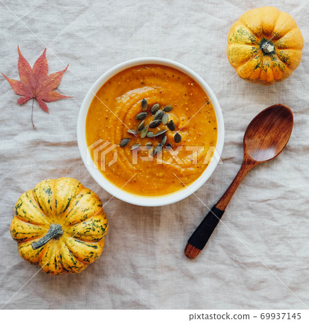 Hot pumpkin soup served with squash seeds in a bowl. Hot pumpkin soup served with squash seeds in a bowl. 69937145