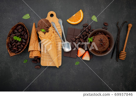 Chocolate ice cream flavours in bowl with dark chocolate and cacao nibs setup on dark stone background . Chocolate ice cream flavours in bowl with dark chocolate and cacao nibs setup on dark stone background . 69937846