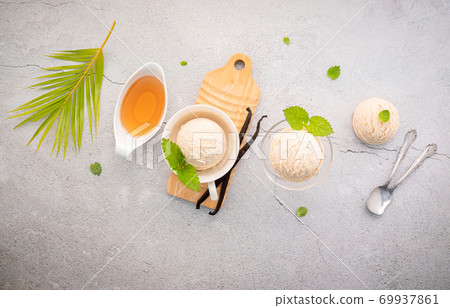 Vanilla ice cream flavor in bowl with vanilla pods setup on concrete background . Summer and Sweet menu concept. Vanilla ice cream flavor in bowl with vanilla pods setup on concrete background . Summer and Sweet menu concept. 69937861
