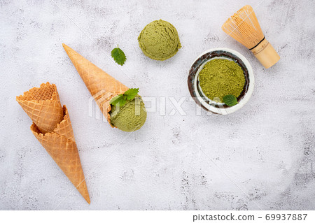 Matcha green tea ice cream with waffle cone and mint leaves setup on white stone background . Summer and Sweet menu concept. Matcha green tea ice cream with waffle cone and mint leaves setup on white stone background . Summer and Sweet menu concept. 69937887