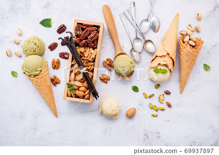 Pistachio and vanila ice cream in cones with mixed nut setup on white stone background . Summer and Sweet menu concept. Pistachio and vanila ice cream in cones with mixed nut setup on white stone background . Summer and Sweet menu concept. 69937897