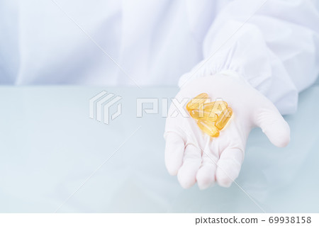 Close up Scientist holding Omega 3 capsule in labcoat 69938158
