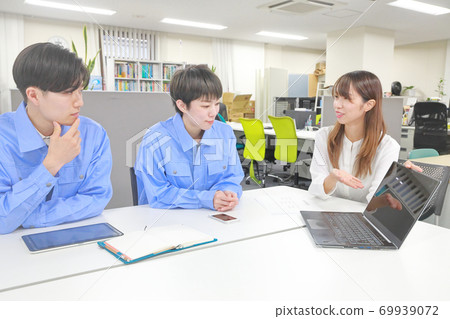 A woman in the sales position who introduces electronic components to engineers using a notebook PC 69939072