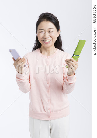 A woman with a smartphone and a feature phone A woman with a smartphone and a feature phone 69939556