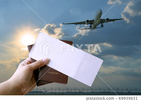 hand holding boarding pass and passport book with plane flying background 69939831