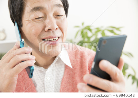 A man looking at a smartphone while making a phone call 69940148