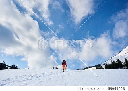 Skier tourist with backpack on background of bright blue sky and beautiful mountain panorama. 69941628