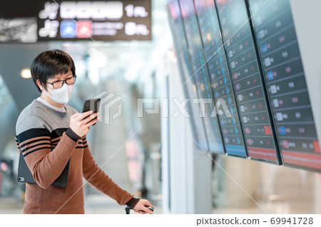 Asian man tourist wearing mask in airport terminal Asian man tourist wearing mask in airport terminal 69941728
