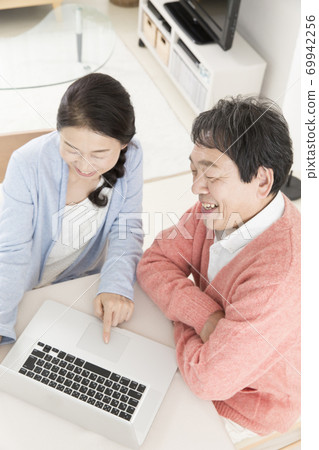 Middle-aged couple using laptop Middle-aged couple using laptop 69942256