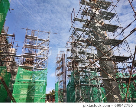 SELANGOR, MALAYSIA -AUGUST 4, 2020: Temporary stairs and scaffolding are used in the construction of high concrete columns. Scaffolding is wrapped with safety netting for safety purposes. 69942790