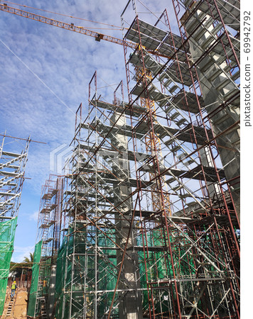 SELANGOR, MALAYSIA -AUGUST 4, 2020: Temporary stairs and scaffolding are used in the construction of high concrete columns. Scaffolding is wrapped with safety netting for safety purposes. 69942792