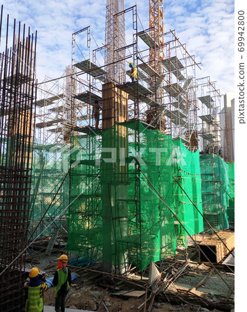 SELANGOR, MALAYSIA -AUGUST 4, 2020: Temporary stairs and scaffolding are used in the construction of high concrete columns. Scaffolding is wrapped with safety netting for safety purposes. SELANGOR, MALAYSIA -AUGUST 4, 2020: Temporary stairs and scaffolding are used in the construction of high concrete columns. Scaffolding is wrapped with safety netting for safety purposes. 69942800