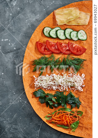 Homemade shawarma, burrito, chicken and salmon roll with vegetables and sauce. Top view ingredients with clear space. Homemade shawarma, burrito, chicken and salmon roll with vegetables and sauce. Top view ingredients with clear space. 69943027