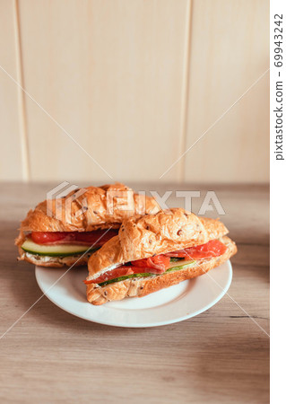 French croissant with cucumber salmon on white plate, Vertical photo orientation French croissant with cucumber salmon on white plate, Vertical photo orientation 69943242