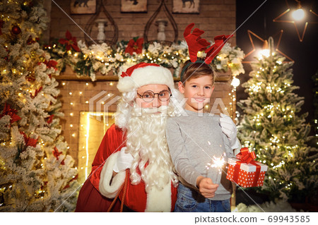 Santa gives presents to children in a room at Christmas Santa gives presents to children in a room at Christmas 69943585