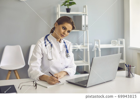 Woman doctor making notes during online lesson or video call consultation in medical clinic Woman doctor making notes during online lesson or video call consultation in medical clinic 69943815