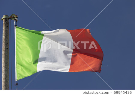 Italian flag blowing in the wind in the blue sky 69945456