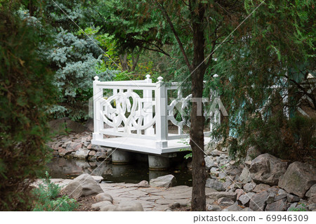 White wooden gazebo in a summer green park. Cozy garden alcove to spend time 69946309