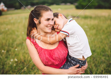 Woman spends time with a child in nature. Mother and son embracing in the park. Happy mom playing with her boy in the field on a glade. Having fun mama and toddler outdoor on summer day 69946491