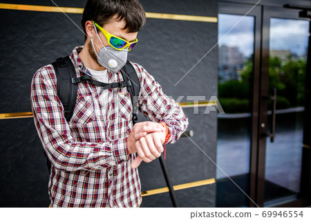 Male courier wearing protective face mask arrived at delivery address on electric scooter. Subject delivery during covid 19 on environmentally friendly transport. Pollution in big city. PM 2.5 mask Male courier wearing protective face mask arrived at delivery address on electric scooter. Subject delivery during covid 19 on environmentally friendly transport. Pollution in big city. PM 2.5 mask 69946554