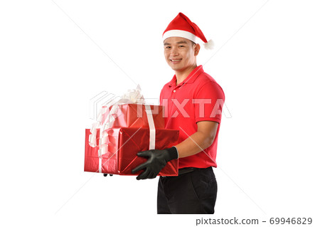 Delivery man in red uniform, face mask, protective gloves, Christmas hat carry boxes of presents  69946829