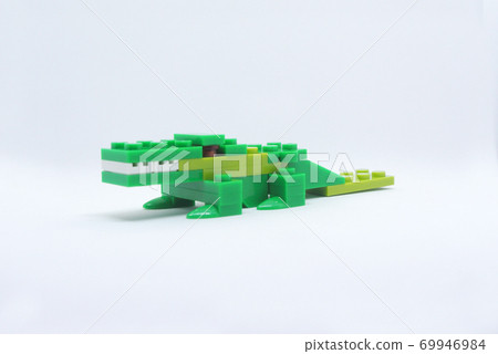The shape of a green crocodile is made from colorful plastic toy bricks. 69946984